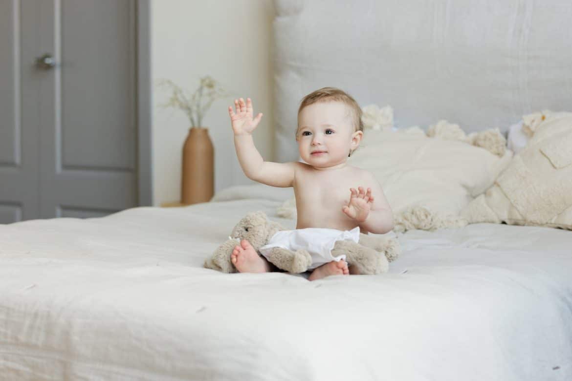 un bébé assis sur un lit 2 places