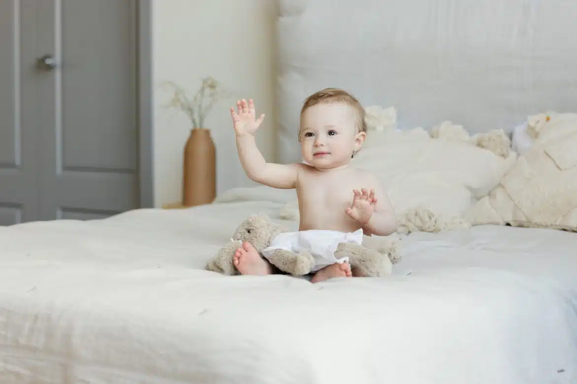 un bébé assis sur un lit 2 places